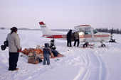 A Cree family watch supplies arrive in a small plane landed on the lake ice. Quebec. Canada. 1988