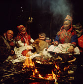 Sami family, Johan-Hendrik, Inge-Anna, Nils-Peter, Berit Logje cook over the fire in the Lavo. Migration. Norway. 1972