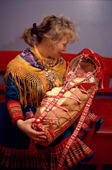 Sami mother with her baby in traditional cradle at christening. Kautokeino, Norway. 1990