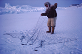 During the polar night, Inuit hunter, Ituko, dressed in furs, sets nets under the ice to catch seals. Moriussaq Northwest Greenland. 1980