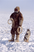 With lasso at the ready, a Dolgan reindeer herder waits with his dog during a winter round up on the tundra. Taymyr, Northern Siberia, Russia. 2004
