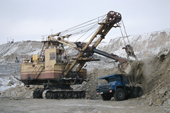 A giant digger loads ore into the back of truck at an open mine near Norilsk. Western Siberia, Russia. 2000
