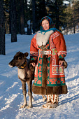 Sveta Pyak, a Khanty woman, with 'Ava,' her pet reindeer calf. She is wearing traditional Khanty winter reindeer skin clothing. Numto, Khanty Mansiysk, Northwest Siberia, Russia