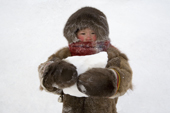 Shura Khudi, a Nenets girl, warmly dressed in reindeer skin clothing, carries snow to melt for water. Yamal, NW Siberia, Russia