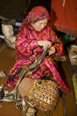 Yevdokiya Tayshen, a Khanty woman, sewing a pair of reindeer skin boots inside her tent. Yamal, Western Siberia, Russia