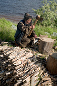 Tamara Khudi, a Nenets woman, chopping firewood at a fishing camp on the River Taz. Tazovsky Region, Yamal, NW Siberia, Russia