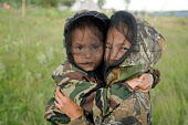 Two young Nenets girls, dressed in protective clothing with mosquito net while playing outside in the summer at a fishing camp on the River Taz. Tazovsky Region, Yamal, NW Siberia, Russia