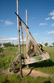 At a Nenets fishing camp on the River Taz, children play on an improvised swing. The swing is made from old fishing net with a wooden fish box as the seat. Tazovsky Region, Yamal, NW Siberia, Russia