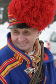 Sami man in a traditional red pompom hat leads the procession at Jokkmokk's Winter Market. Sweden. Size to A4